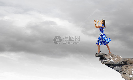 女人玩Fife轻的女人穿着蓝色的衣服,站岩石上玩飞弹图片