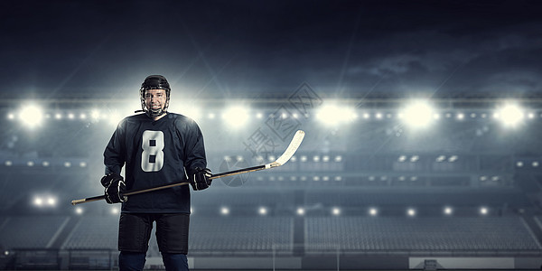 冰球运动员冰上穿着蓝色制服的曲棍球运动员聚光灯下的冰场上图片