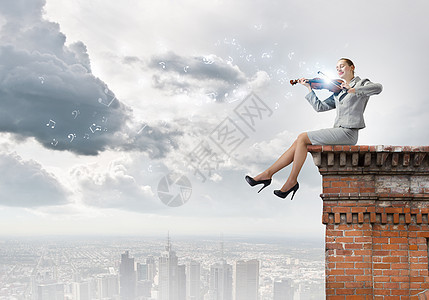 女小提琴手轻的女商人坐建筑物的顶部拉小提琴背景图片