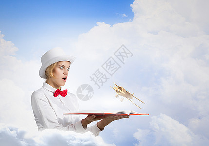 炸毁你想象力的书轻的女人戴着白色的帽子,手里着打开的书,飞机飞了出图片
