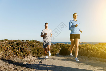 运动跑步者海滩上慢跑,她的搭档锻炼适合女健身模式慢跑沿海洋与她的伴侣图片