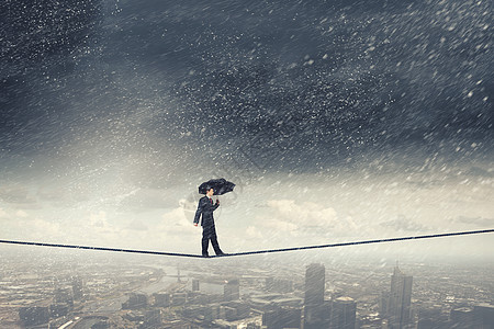 生意上的悲观主义者带着黑色雨伞走绳子上的商人图片