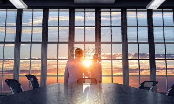 办公室里商人的剪影两个商人日落的灯光下办公室握手图片