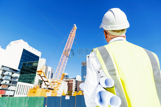 建筑工地的工程师建设者工程师建筑工人施工场景穿着带蓝图的安全背心图片