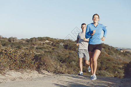 运动跑步者海滩上慢跑,她的搭档锻炼适合女健身模式慢跑沿海洋与她的伴侣图片