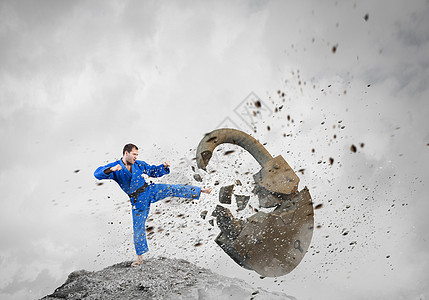 穿着蓝色基米诺的空手道男人轻果断的空手道男子打破愤怒的混凝土锁