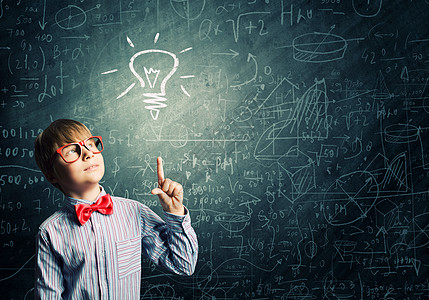 聪明的小学生戴着红色眼镜的天才男孩靠近黑板,公式背景图片