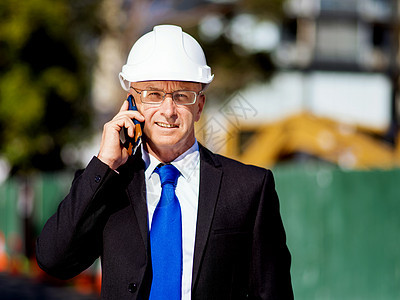 建筑工地的商人施工场景,司机戴着安全帽,带着手机图片