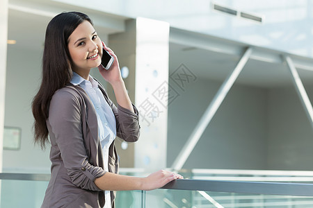 办公楼里魅力的女人轻的黑发女人现代璃室内用手机说话图片