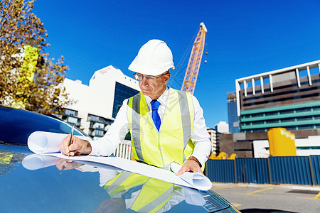 建筑工地的工程师建设者工程师建筑工人施工场景穿着带蓝图的安全背心图片