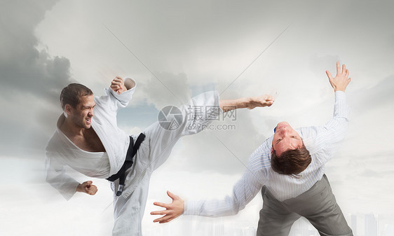 穿着白色基米诺的空手道男人轻坚定的空手道男子与西装革履的商人打架图片