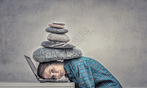 石头柱子工作的压力下女程序员用沉重的石头压笔记本电脑上背景