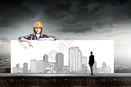 轻的女建筑工人戴着头盔,手持建筑工程横幅发展项目图片