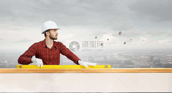 轻的工程师建筑工人穿着检查衬衫用测量水平图片