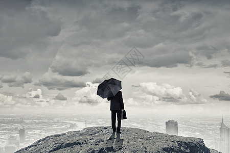 带着黑色雨伞的人站山顶上的商人带着雨伞手提箱的背景图片