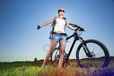 公园里骑自行车的轻美女的低角度夏季自行车步行图片