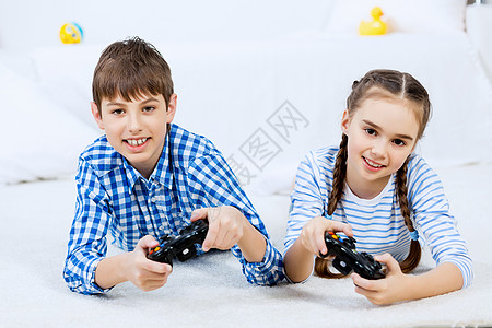 孩子们玩游戏控制台可爱的孩子躺地上,操纵杆上玩游戏图片