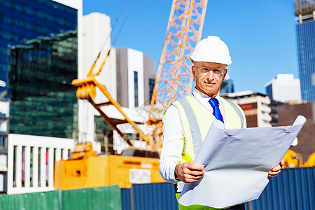 建筑工地的工程师建设者工程师建筑工人施工场景穿着带蓝图的安全背心图片