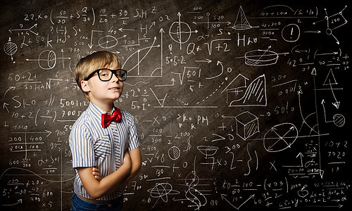 聪明的小学生戴着红色眼镜的天才男孩靠近黑板,公式图片