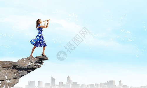 女人玩Fife轻的女人穿着蓝色的衣服,站岩石上玩飞弹图片