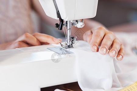 缝纫裁剪裁缝工作室密切妇女裁缝的手与缝纫机工作背景