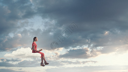 女人读书轻的女人穿着连衣裙,手里着旧书,坐云上图片