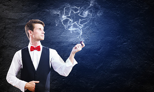 抽烟斗轻英俊的商人黑色背景下抽烟斗图片