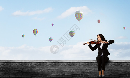 女小提琴手轻的女人坐楼顶上拉小提琴图片