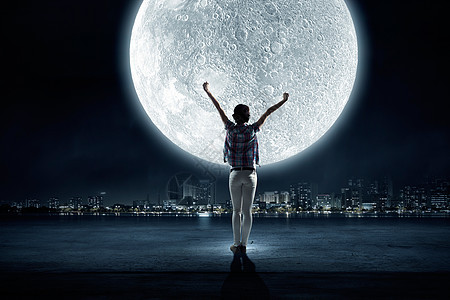 满月轻女人的后视镜,举手看着天空中的月亮图片