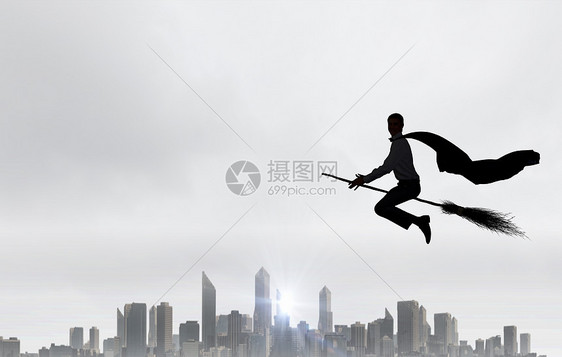 男人骑扫帚轻的商人高空的扫帚上飞翔图片
