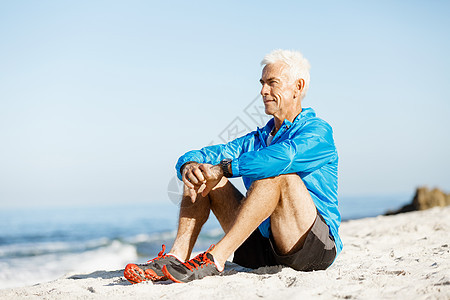 穿着运动服的男人坐海滩上运动中的男人穿着独自坐海滩上休息分钟图片