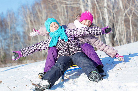 冬天的乐趣两个可爱的女孩美丽的雪冬公园里享受雪橇图片