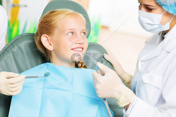 牙齿检查可爱的微笑女孩坐扶手椅上看牙医图片