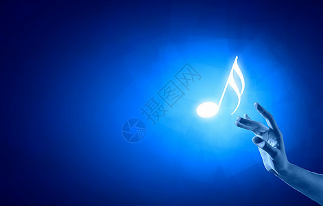 音乐音符特写人手触摸蓝色背景上的音乐符号图片