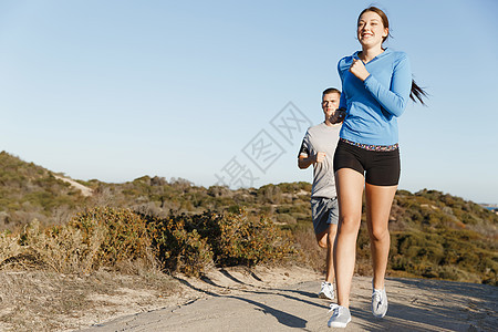 运动跑步者海滩上慢跑,她的搭档锻炼适合女健身模式慢跑沿海洋与她的伴侣图片