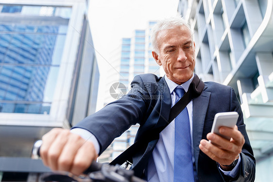 成功的商人骑自行车成功的商人穿着西装骑自行车着手机图片