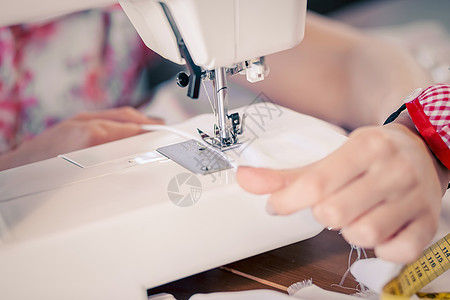 裁缝工作室轻的女裁缝缝纫机上工作图片