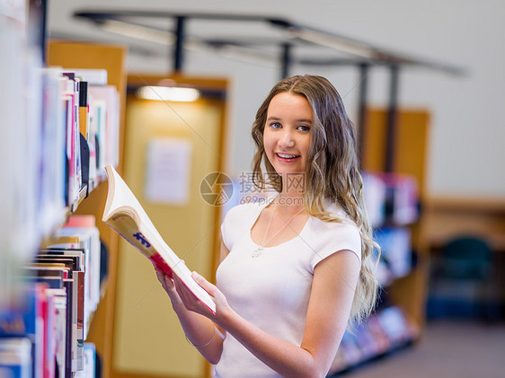 快乐的年轻女学生图书馆选书图片