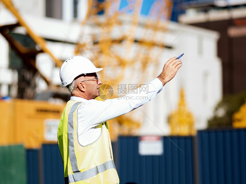 建筑工地的工程师建设者工程师建筑工人施工场景穿着安全背心记事本图片