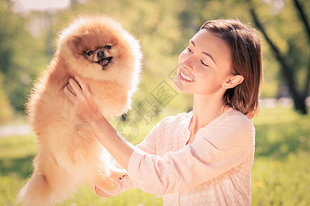 轻的女人夏天的公园狗玩公园带着宠物图片