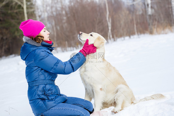 冬天公园里带着拉布拉多狗散步的女孩图片