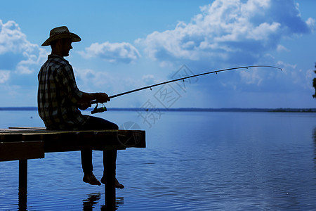 高清图片夏天钓鱼戴帽子的轻人坐桥上钓鱼高清图片夏