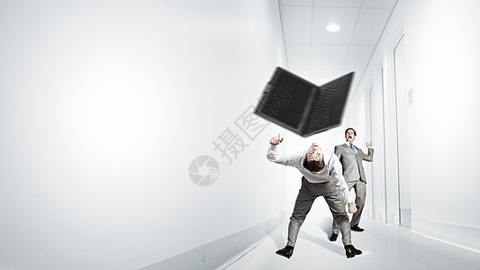 轻的商人试图逃避扔来的笔记本电脑两个商人互相争斗图片