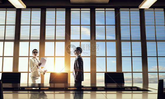 办公室里商人的剪影两个商人日落的灯光下办公图片