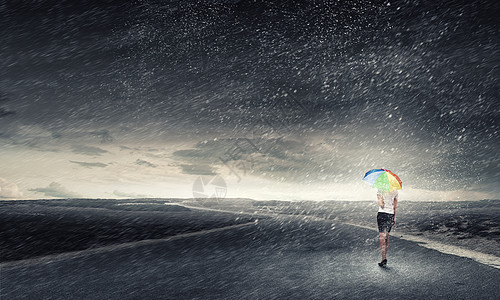 带彩虹伞的女人轻漂亮的女商人带着彩虹五颜六色的雨伞暴风雨中行走图片