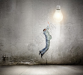 商业理念商人跳跃捕捉灯泡的形象图片