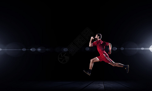 穿着红色运动服的跑步者在黑色上全速前进图片