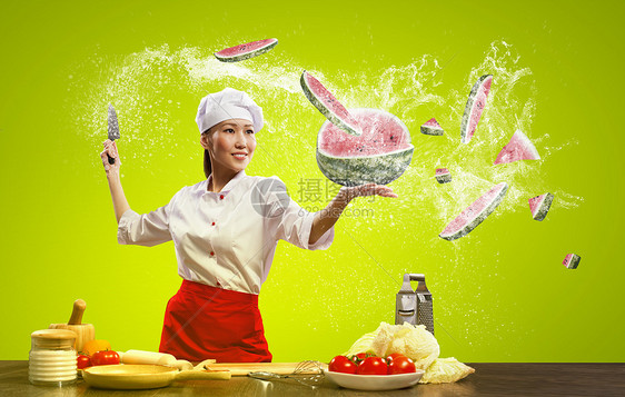 亚洲女厨师用刀子空气中切割水果蔬菜图片