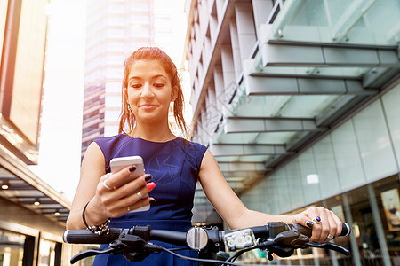轻的女人骑自行车上下轻的商务妇女骑自行车手机图片