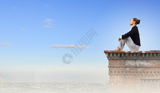 轻迷人的女士坐大楼的顶部图片